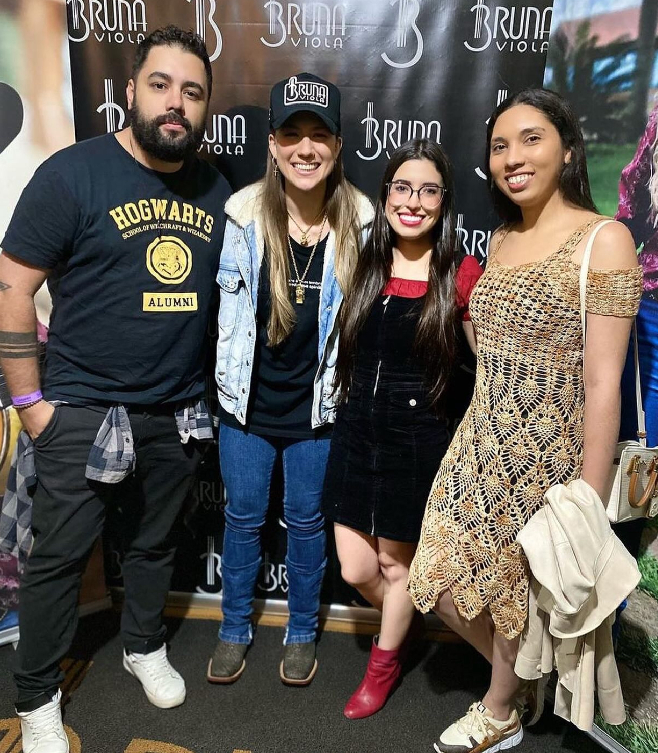 Bruna Viola ao lado da equipe em frente ao painel da artista